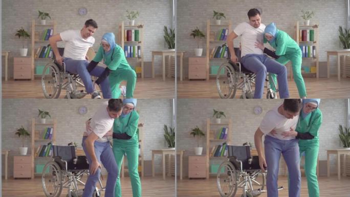 盖头的穆斯林护士在现代诊所帮助残疾人从轮椅上站起来
