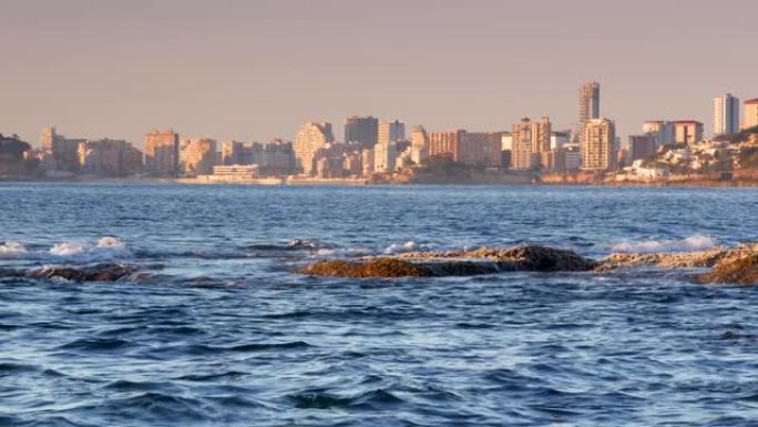 阿尔坎特 (Alicante) 地平线上的卡尔佩市建筑，前景是大海。