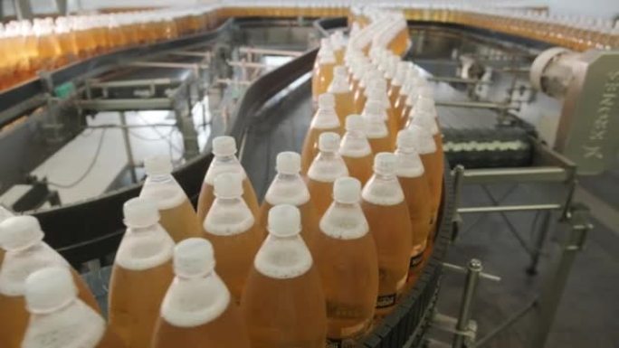 在现代化的饮料厂，带有果汁或水的瓶子的传送带。现代生产甜苏打水