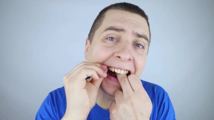 牙线特写。镜子前的一个人用牙线刷牙。适当口腔护理的概念。选择性聚焦。
