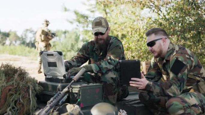 强大军队的士兵们正在准备对抗突然袭击的敌人的战略，将数据输入系统，交谈，手持平板电脑，穿着制服，mo
