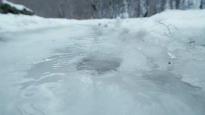 在山路上的鞋印上融化冰，POV，低角度视图。