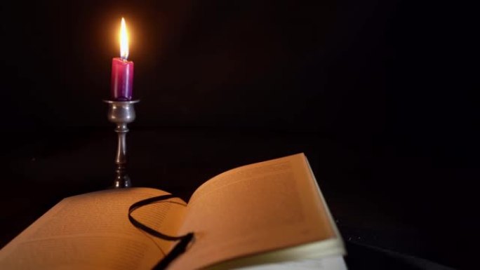 在一本打开的德文书前滑动，在白蜡制的烛台上点着一支短蜡烛