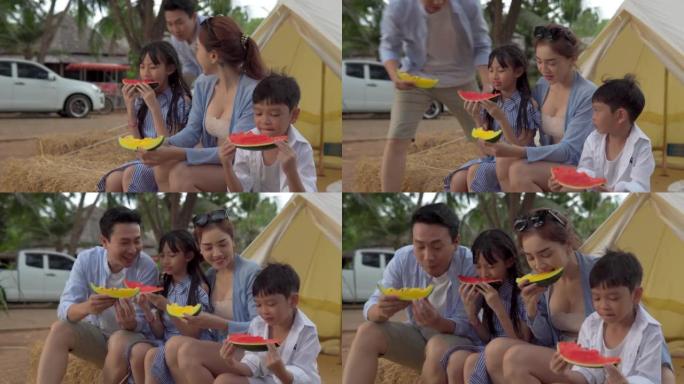 快乐的亚洲家庭在帐篷前度假吃西瓜