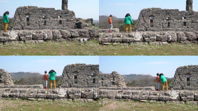 小学生男孩和少年朋友走在阿斯彭多斯古城的石墙上
