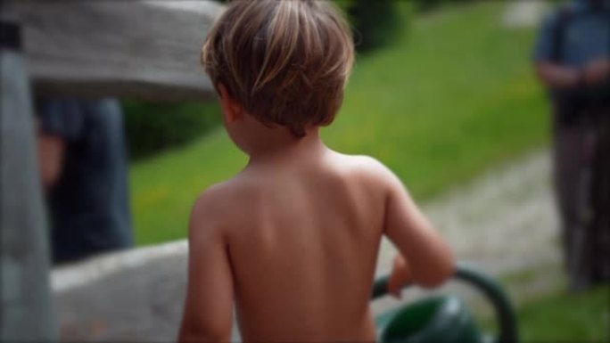 小男孩在外面穿着内衣的花园里拿着喷壶