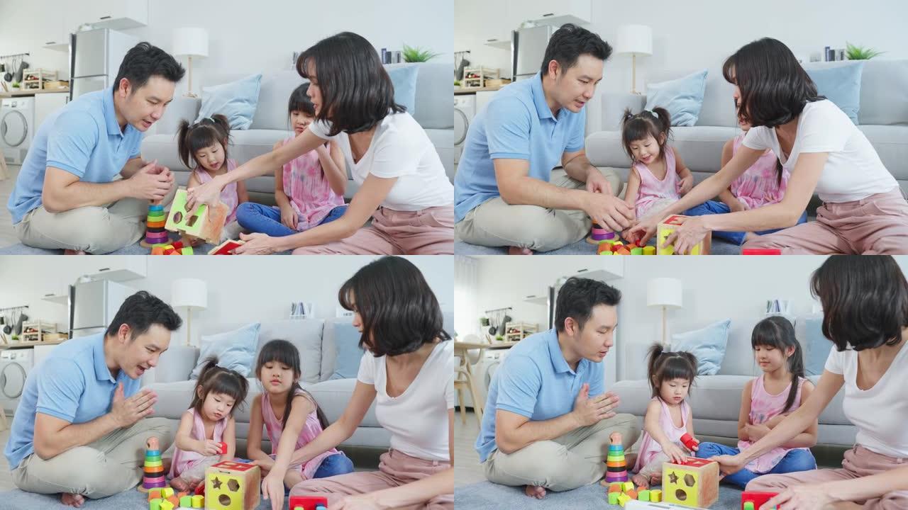 亚洲幸福家庭坐在地板上，在客厅里一起玩儿童玩具。迷人的父母母亲和父亲花时间和年轻的小女孩女儿在家里。