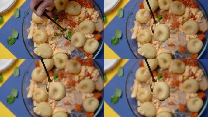 垂直桌面视频: 厨师用勺子用西红柿和羊乳酪煮熟的土豆饺子