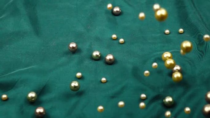 珍珠珠子在绿色的丝绸上滚动，背景，慢动作
