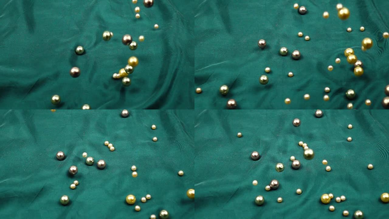 珍珠珠子在绿色的丝绸上滚动，背景，慢动作