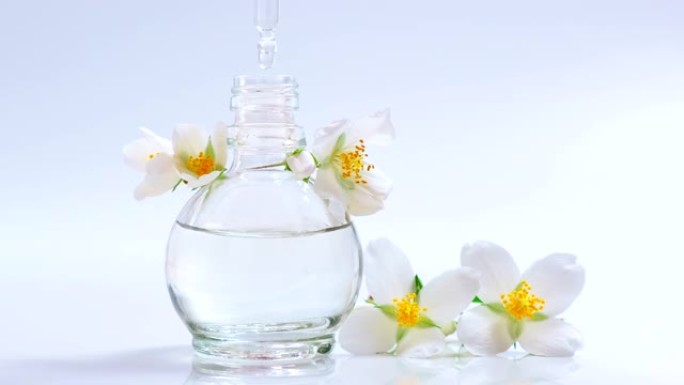香水。精油产品。从化妆品移液器滴落到装有香水的玻璃瓶。皮肤和身体护理。芳香草本植物和花卉液体。美容和