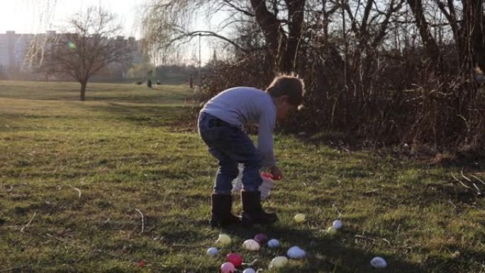 可爱的蹒跚学步的男孩，在公园的篮子里收集复活节彩蛋