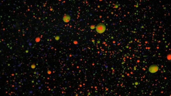 黑色背景上的圆形五彩球，银色亮片。红色、蓝色和绿色颗粒随机移动。