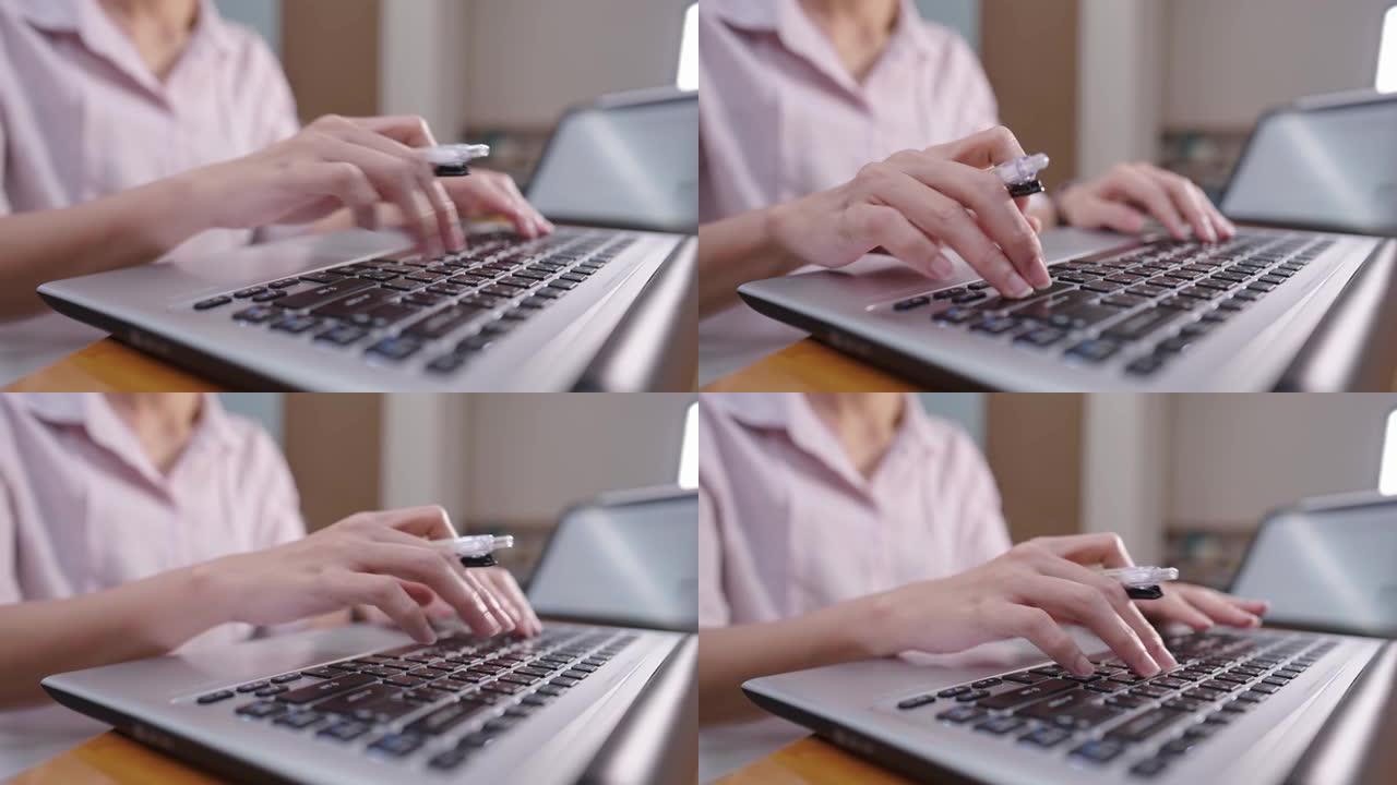 一名女会计工作者坐在办公桌前在笔记本电脑键盘上打字，而手握笔，财务管理工作狂女士，多任务独自工作在截