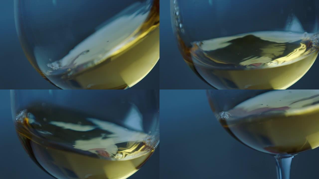 在散焦的深色背景上，在玻璃杯中挥舞金色白葡萄酒。美丽的葡萄酒广告素材。高脚杯内葡萄酒混合过程的特写视
