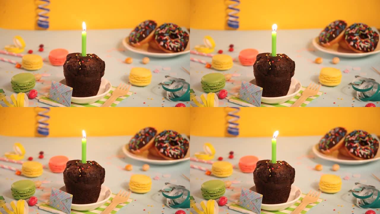 美味的巧克力松饼纸杯蛋糕，背景为生日蜡烛和其他糖果。党的概念。