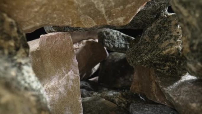 相机在黑色背景下的一堆灰色和棕色花岗岩中平移。粗糙的花岗岩砾石鹅卵石，具有天然质地和断裂图案。地质。