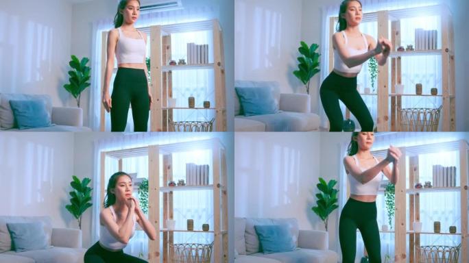 亚洲年轻美丽的积极运动女人在家做有氧运动。穿着运动服的迷人女孩用垫子在家里的客厅花免费的休闲时间锻炼