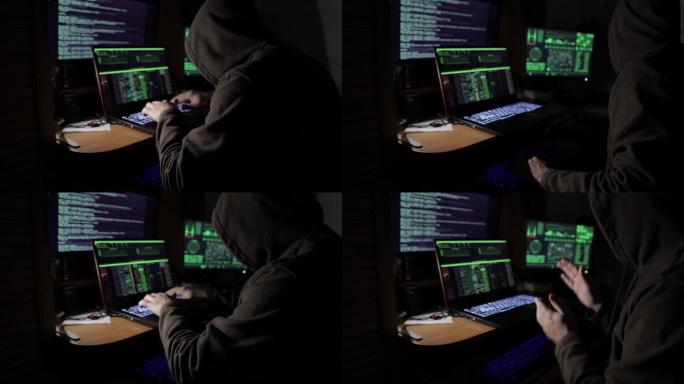 一名黑客在暗室里的显示器前试图黑进安全系统