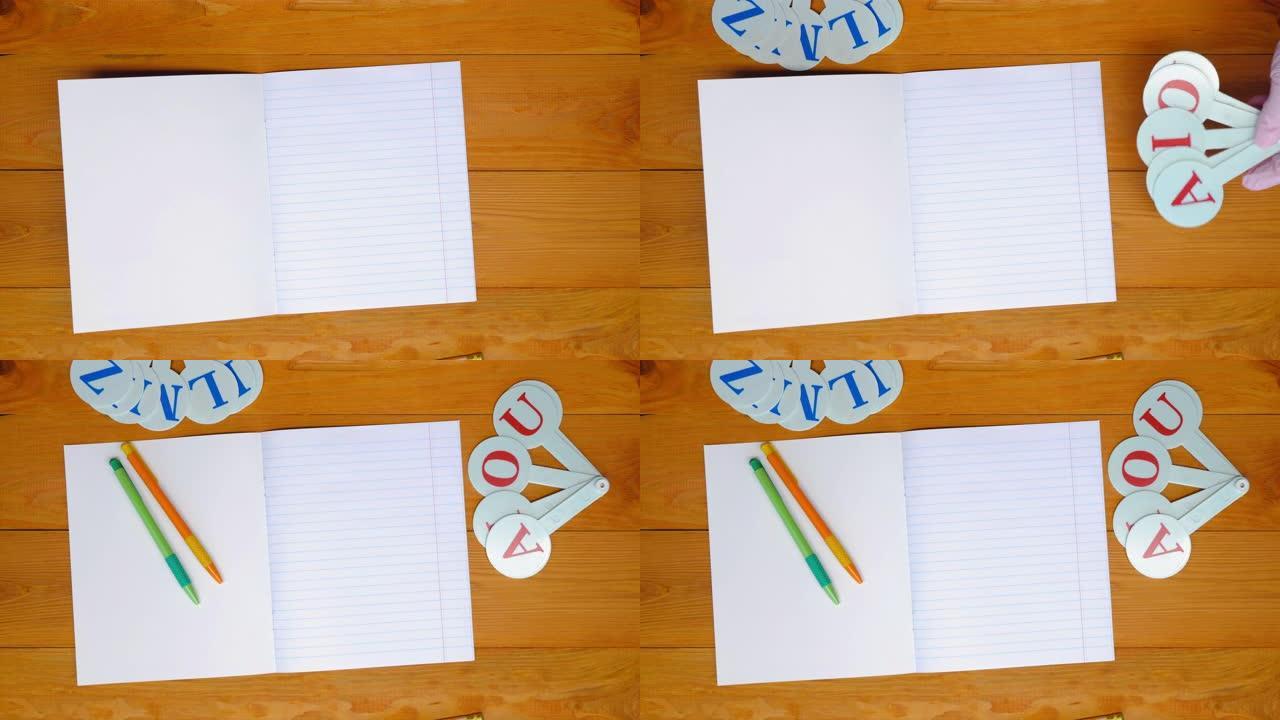 学校老师在学前班教室的木桌上排成一排的笔记本，彩色笔和字母，用于学习拼写。复制文本空间。空白单页。顶