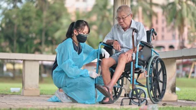 亚洲华裔女性理疗师指导轮椅上的老人伸展腿部