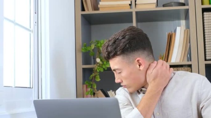 特写后视强调年轻人触摸下颈部感到不适，由于久坐的生活方式或在家庭办公室以不正确的姿势长时间电脑过度劳