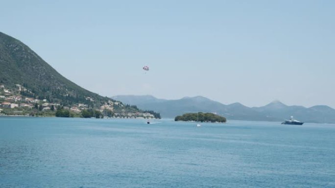 地中海岛屿景观。快艇，游客在降落伞后沿着海岸线飞行