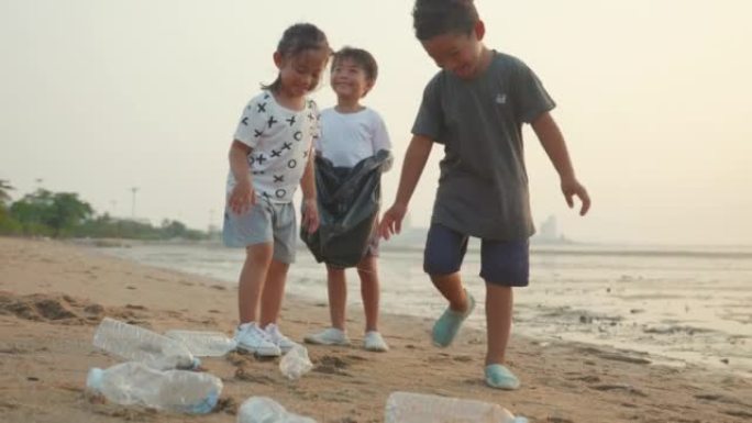 志愿者快乐家庭的孩子把塑料瓶放进黑色的垃圾塑料袋里清洁海滩