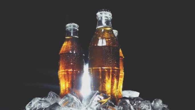 玻璃湿的苏打水在冰块中的旧瓶子在光线中孤立的黑色背景上转成一圈。具有速度斜坡效果的4k慢动作视频。