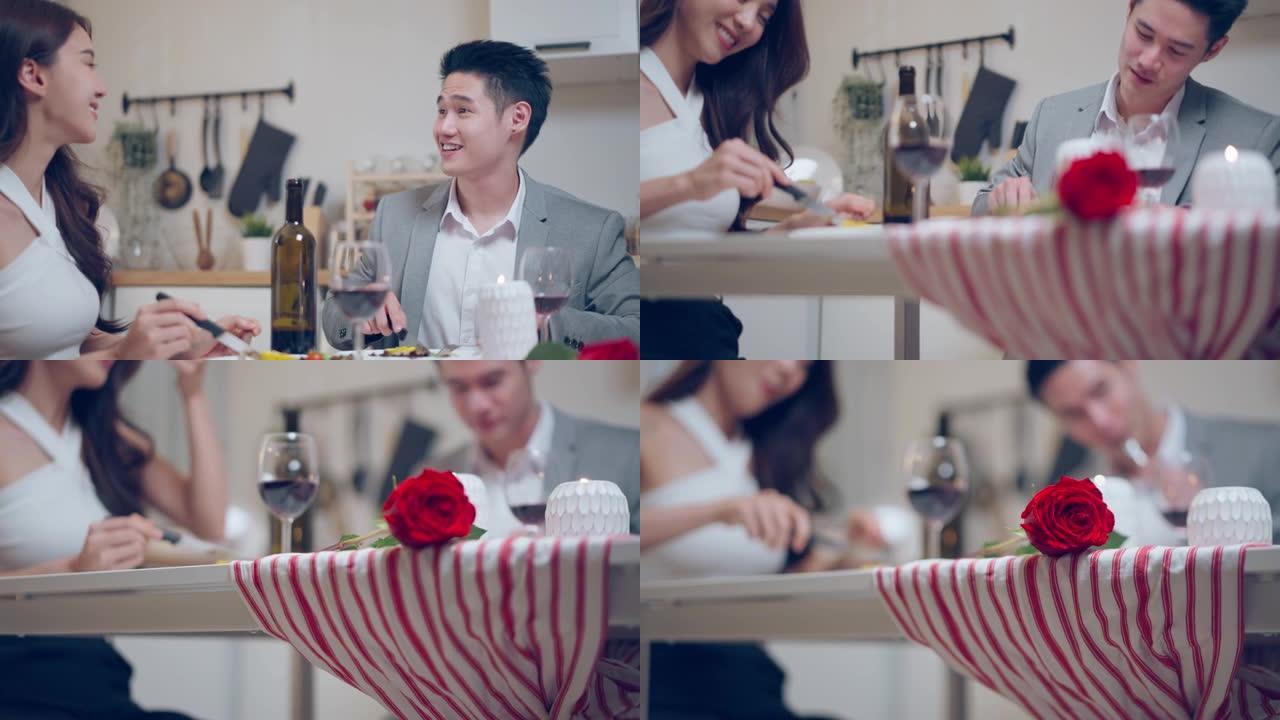 亚洲年轻夫妇共进晚餐，一起庆祝情人节。迷人的浪漫新婚男女在家里的厨房里吃结婚纪念日的食物。