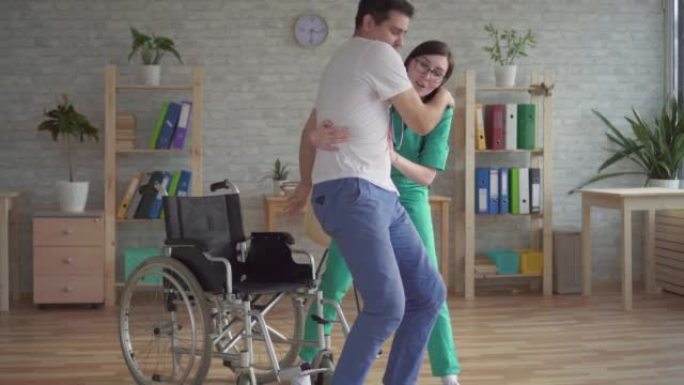 女护士在现代诊所帮助残疾人从轮椅上站起来
