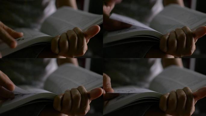 关闭女人的手握着书的翻页。无法识别的人阅读教科书并动动手指以找到所需的内容。