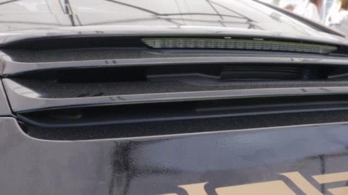 一辆闪亮的保时捷911跑车，带有反光黑色油漆。活动后扰流板和尾灯的详细信息。汽车细节概念。车展上带有