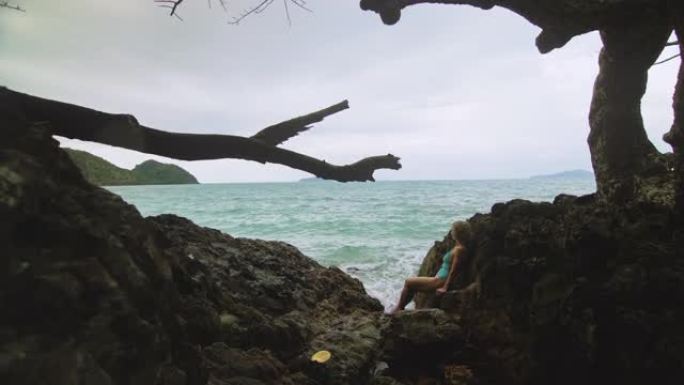 女人冥想，在暴风雨的早晨多云的海面上，在岩石裂缝礁山上放松。概念女性，性阴道健康，女性，自由，新鲜