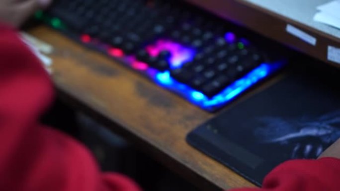 穿着红色连衣裙的男孩用台式电脑玩游戏娱乐。