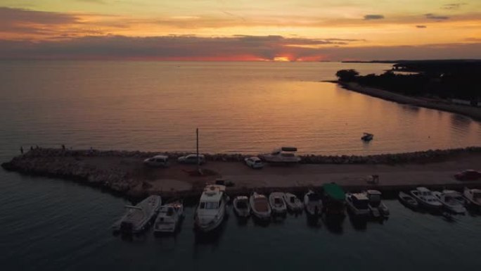 夏天在克罗地亚亚得里亚海地中海的海滨海湾港口日落，假日度假旅游船和渔船在码头上。空中无人机空中飞行从