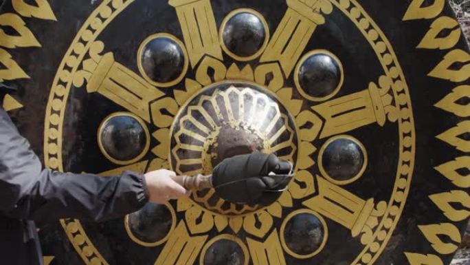 一个游客在泰国寺庙敲击一个巨大的东方锣钟