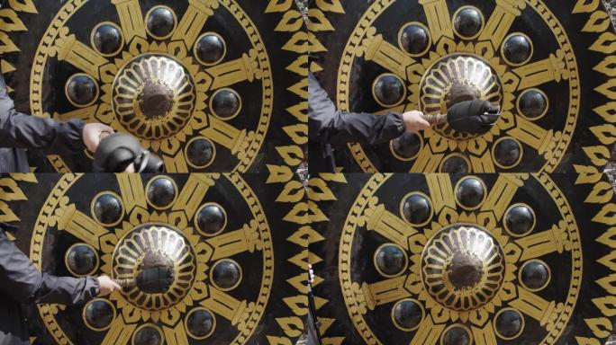 一个游客在泰国寺庙敲击一个巨大的东方锣钟