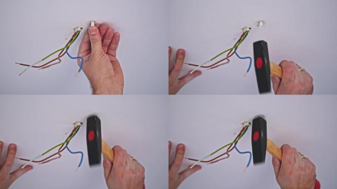 高加索男性杂工将膨胀插头锤击到天花板上靠近电源线的孔中，以安装灯
