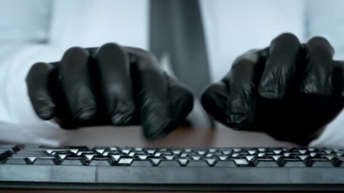 双手戴着黑色手套在键盘上打字。