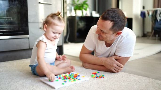 可爱的小女孩玩蘑菇指甲马赛克。父亲和婴儿一起玩的概念。爱好和休闲时间