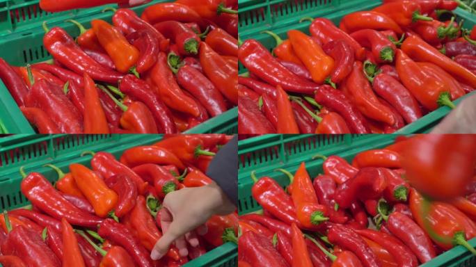 手的特写镜头从超市货架上取红甜椒放在袋子里