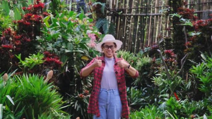 微笑的园丁女人站在温室里的花卉植物上。在花园工作的年轻女企业家。小企业主的启动。