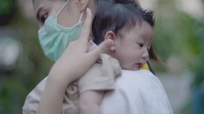亚洲母亲将刚出生的婴儿抱在肩上，并在房子里散步。