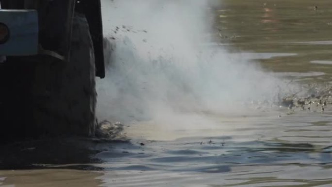 极端越野车轮在肮脏的水中旋转，它冒烟