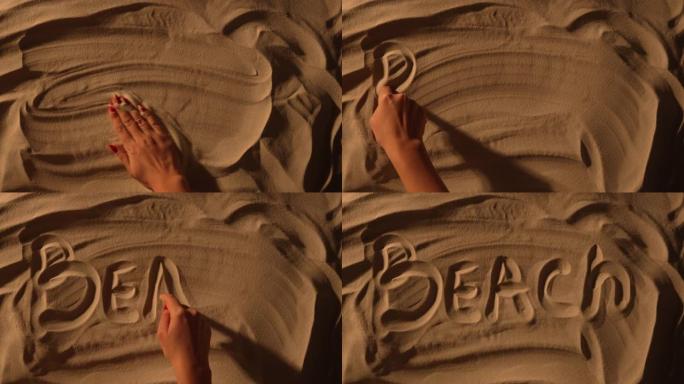 女性手抚平沙质表面并绘制铭文海滩。女人在沙滩上写字。海边的暑假，享受海滩的假期。慢动作。特写