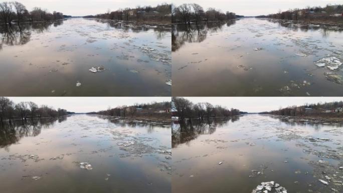 几只又大又脏的白色浮冰沿着阴沉的河水漂浮。