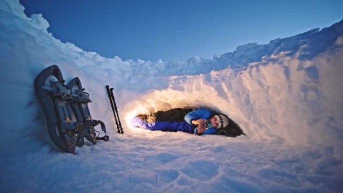 成熟的游客晚上在雪地里的避难所里使用电话。在大自然中独自在冬山露营。