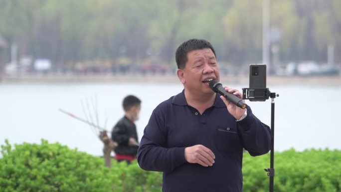 公园里中年男人对着手机唱歌娱乐
