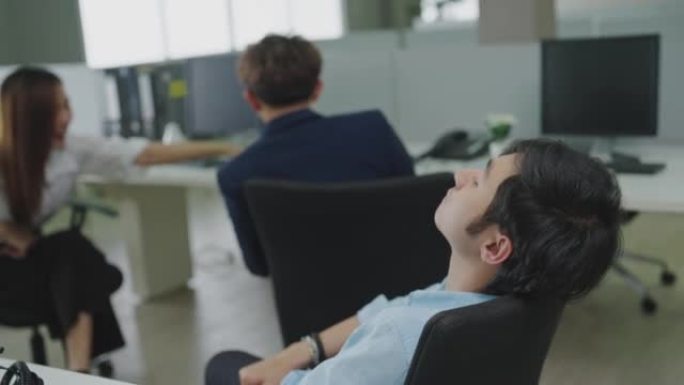 亚洲男性上班族睡在办公室的椅子上。